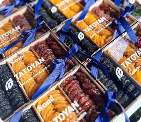 Wooden gift boxes tied with blue ribbon, filled with dried apricots, plums, and raisins under a custom client logo